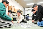 身を乗り出して勢いよく札を取る児童＝５日、香美町香住区大野の長井地区公民館