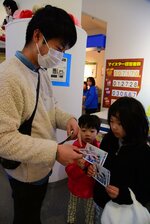 記念のポストカードを手に喜ぶ家族連れ＝１５日、北栄町由良宿の青山剛昌ふるさと館