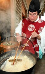 鉄鍋からかゆが詰まった竹筒を取り出す太田宮司＝１２日、大山町松河原の逢坂八幡神社