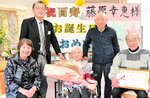 家族や浜上町長らに囲まれ、１００歳の誕生日を迎えた藤原さん（前列中央）＝２９日、香美町小代区神水の特別養護老人ホームこぶし園