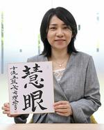 「慧眼」と書いた色紙を手にする女流棋士の矢内理絵子さん