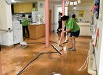 床上２０㌢まで漬かった大雨被害の後片付けに追われる職員ら＝１４日、鳥取市福部町湯山のグループホームわかばの家福部