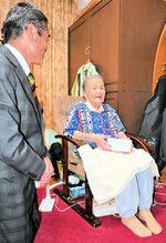 記念品の膝掛けをして長寿の秘訣を伊達市長（左）に話す足立さん＝１５日、境港市幸神町