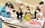 渡辺さん（手前左）が牛肉をスライスする様子を見学する参加者＝１日、新温泉町丹土の県立但馬牧場公園