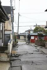 　能登半島地震による液状化でひび割れた道路と傾く電柱＝１月、新潟市西区