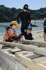 　月浜海水浴場の砂浜でいかだ造りをする小学生ら＝宮城県東松島市