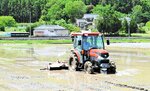 水を浅く張った田で「浅水代かき」を行う稲作農家＝２３日、米子市奥谷