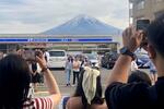 　コンビニの屋根越しの富士山を撮影する観光客ら＝４月、山梨県富士河口湖町
