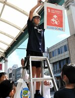 掲出用のポールに垂れ幕を取り付ける児童＝４日、鳥取市の若桜街道商店街