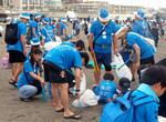 　片瀬東浜海水浴場で青色のサンタ姿で清掃活動をするイベントの参加者＝１５日午後、神奈川県藤沢市