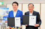 協定書を手にする松浦町長（右）と国井町長＝３日、三朝町大瀬の町総合文化ホール