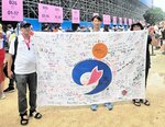 １３～１６位決定戦終了後に南部町旗の寄せ書きを掲げる（左から）古田浩明さん、直輝選手、尚子さん＝７月３１日、フランスのヴェール・シュル・マルヌ・ノーティカル・スタジアム（古田浩明さん提供）