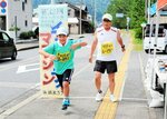 中継点でたすきを受け取って走り出す参加者（左）＝８日、新温泉町芦屋の浜坂海岸レクリエーションセンター前