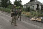 　８日、ウクライナ東部ドネツク州の前線付近で、ロシア軍の攻撃で破壊された住宅の前を歩くウクライナ軍の兵士（ロイター＝共同）