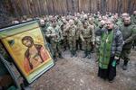 　ウクライナ東部ルガンスク州のロシア側支配地域で、ロシア兵らと共にクリスマスイブの祈りをささげる正教会の司祭（右手前）＝６日（タス＝共同）