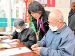 新温泉町社会福祉協議会の職員（中央）に教わりながらキットを作る買い物客＝３１日、同町浜坂のスーパー「ナカケー白川店」