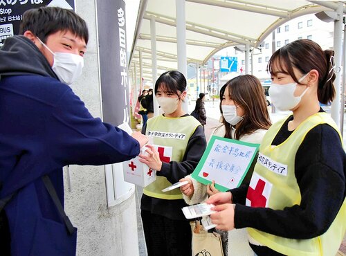 学生たちの呼びかけに募金をするＪＲ倉吉駅の利用者（左）＝１５日、ＪＲ倉吉駅南口駅前広場