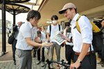 自民党総裁選の結果を伝える号外を受け取る男性＝２７日、ＪＲ鳥取駅前