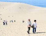 汗をぬぐいながら砂丘を歩く観光客＝２日午後１時ごろ、鳥取市湯山の鳥取砂丘