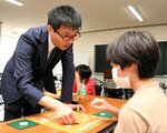 対局を通じて子どもたちに指し手を指南する宮本五段（左）＝１８日、倉吉体育文化会館