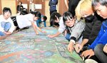 大学生（右から２人目）らと一緒にチョークアートに取り組む児童＝２５日、智頭町郷原の旧山形小学校