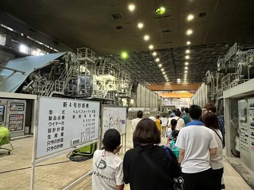 日本海新聞の新聞用巻取紙を製造する第四号抄紙機を見学する参加者たち