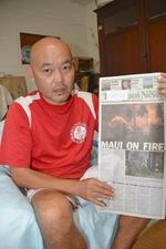 　自身の寺が燃える写真を載せた地元紙マウイ・ニュースを手にする広中愛さん＝１７日、米ハワイ・マウイ島カフルイ（共同）