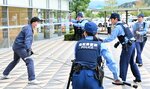 刃物を持った不審者（左）を制圧する署員ら＝２４日、倉吉市のエースパック未来中心