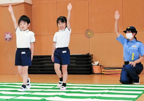 手を高く上げて横断歩道を渡る園児