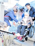 補助装置を付けた車椅子で階段を下りる参加者＝１８日、新温泉町湯の荒湯付近