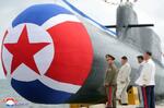　新たに建造された「戦術核攻撃潜水艦」のそばに立つ北朝鮮の金正恩朝鮮労働党総書記（左から２人目）＝６日（朝鮮中央通信＝共同）