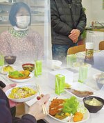 クリスマス交流会で、野上さん（仮名）＝右上＝のあいさつを聞く邨上さん。写真下は手作り料理＝コラージュ