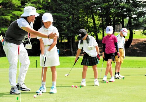 高岡プロ（左）の指導を受けながらパターの練習をする小学生ら