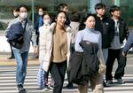 　高気圧の影響で気温が上昇し、上着を手に持ち歩く人たち＝１３日午後、福岡市