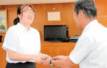 伊達市長（右）から弓浜絣の名刺入れを贈られる金さん＝１０日、境港市役所