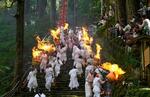 　熊野那智大社の例大祭「那智の扇祭り」で、燃えさかる大たいまつを担ぎ練り歩く白装束の氏子ら＝１４日午後、和歌山県那智勝浦町