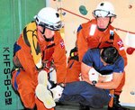 オレンジ色の制服を着て訓練を披露する梶谷さん（左）と吉岡さん＝６日、境港市佐斐神町の第８管区海上保安本部美保航空基地
