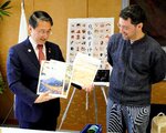 平井知事（左）に県内の景観をモチーフにした工芸品を紹介するティモテ・カプラン氏＝１４日、鳥取県庁