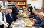 絵巻物を小谷校長（右奥）に寄贈する篠田さん（左から３人目）ら＝篠田さん提供
