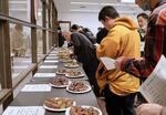 　茨城県行方市で開かれた焼き芋イベントで、１２種のサツマイモを食べ比べる愛好家ら＝２０２５年１月