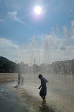焼けるような日差しの下、噴水の水で涼をとる子どもたち＝２日、倉吉パークスクエア
