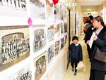 【１５０年の歴史思いはせて】校舎内で開かれた写真展。昭和時代を中心に懐かしいモノクロ写真が数多く並び、訪れた人々が１５０年に及ぶ同小の長い歴史に思いをはせた＝佐津小