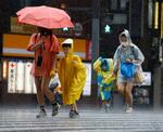 　台風６号の暴風雨に見舞われた鹿児島市中心部を歩く人たち＝８日午後
