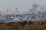 　２１日、パレスチナ自治区ガザで破壊された建物から上がる煙。イスラエル南部から撮影（ロイター＝共同）