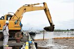 台風の影響で流れ着いた流木や草など大量のごみを撤去する建設業者＝１７日、鳥取市港町