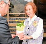 村岡ライオンズクラブの才田会長（左）から花の鉢植えを受け取る中村さん＝３１日、香美町村岡区長須