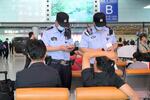 　北京首都国際空港の到着ロビーでパスポートを調べる警察官ら＝１日（共同）