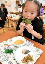 自分で握ったおにぎりをおいしそうに頰張る児童＝２８日、倉吉市の明倫小