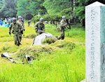 草刈り機や熊手を使って墓地をきれいにする参加者ら＝２３日、鳥取市国府町宮下の旧陸軍墓地
