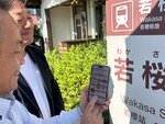 スポットとなっている若桜駅前の看板と照らし合わせながら、謎解きに挑戦する上川町長（手前）